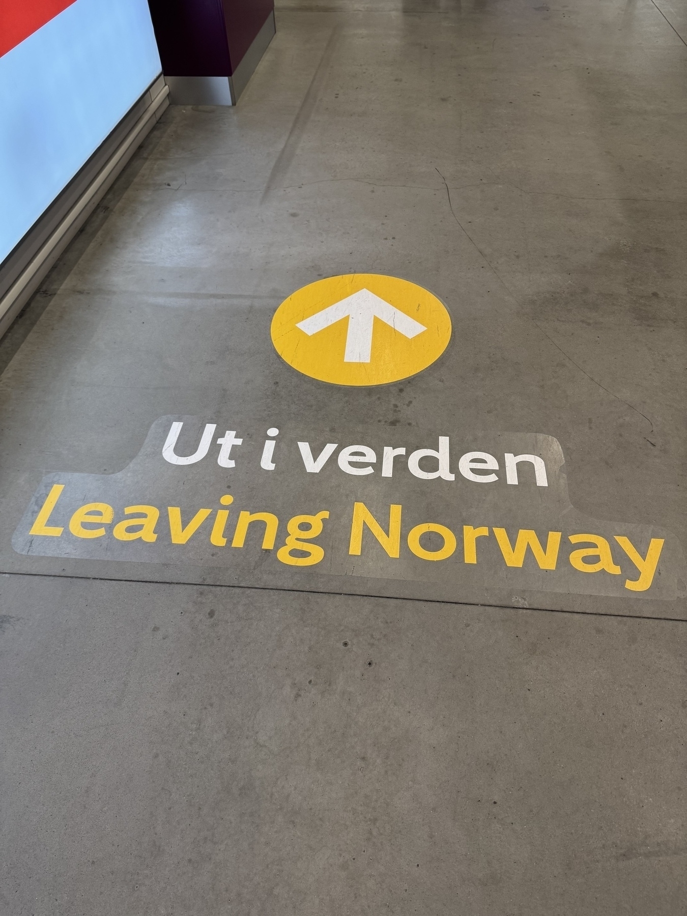 Image of airport floor with a floor sign and arrow saying Leaving Norway in both Norwegian and English 