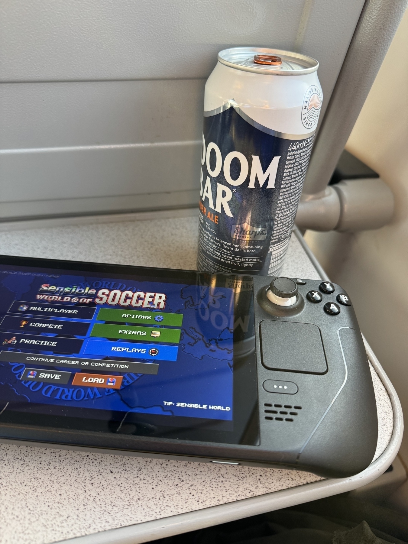 photo of my steamdeck with sensible soccer loaded up and a can of doom bar on the train table