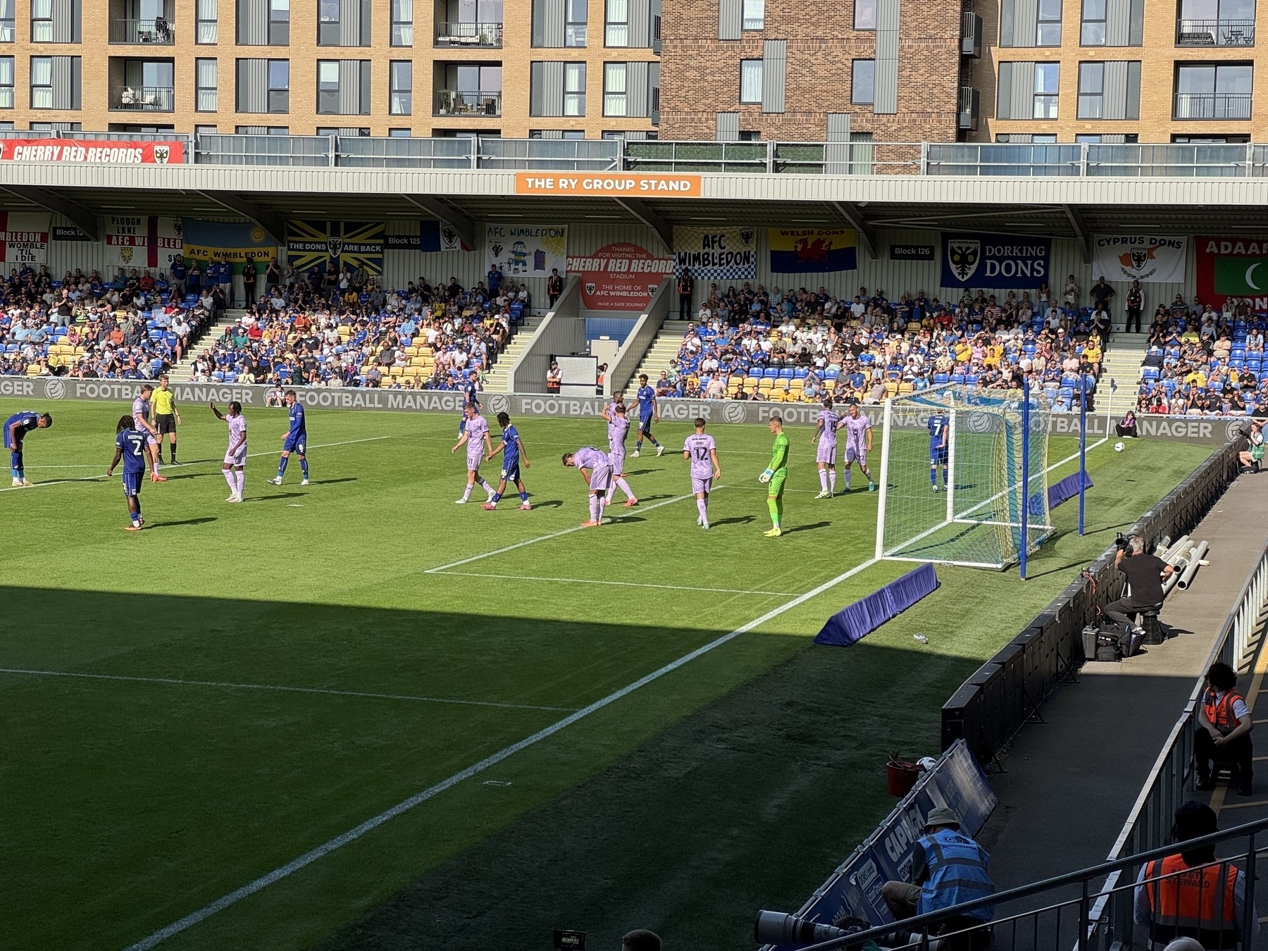 A soccer match is taking place in a stadium with players on the field and spectators in the stands.
