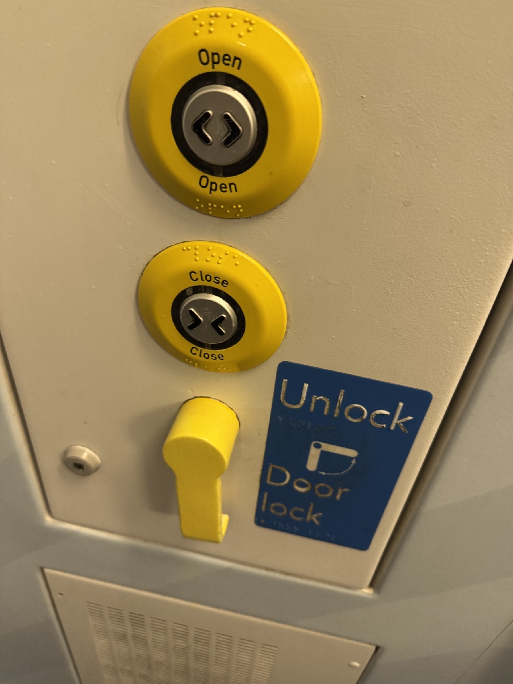 Sw trains toilet - Two circular yellow buttons labeled "Open" and "Close" are positioned above a yellow handle next to a blue sign that reads "Unlock Door lock."
