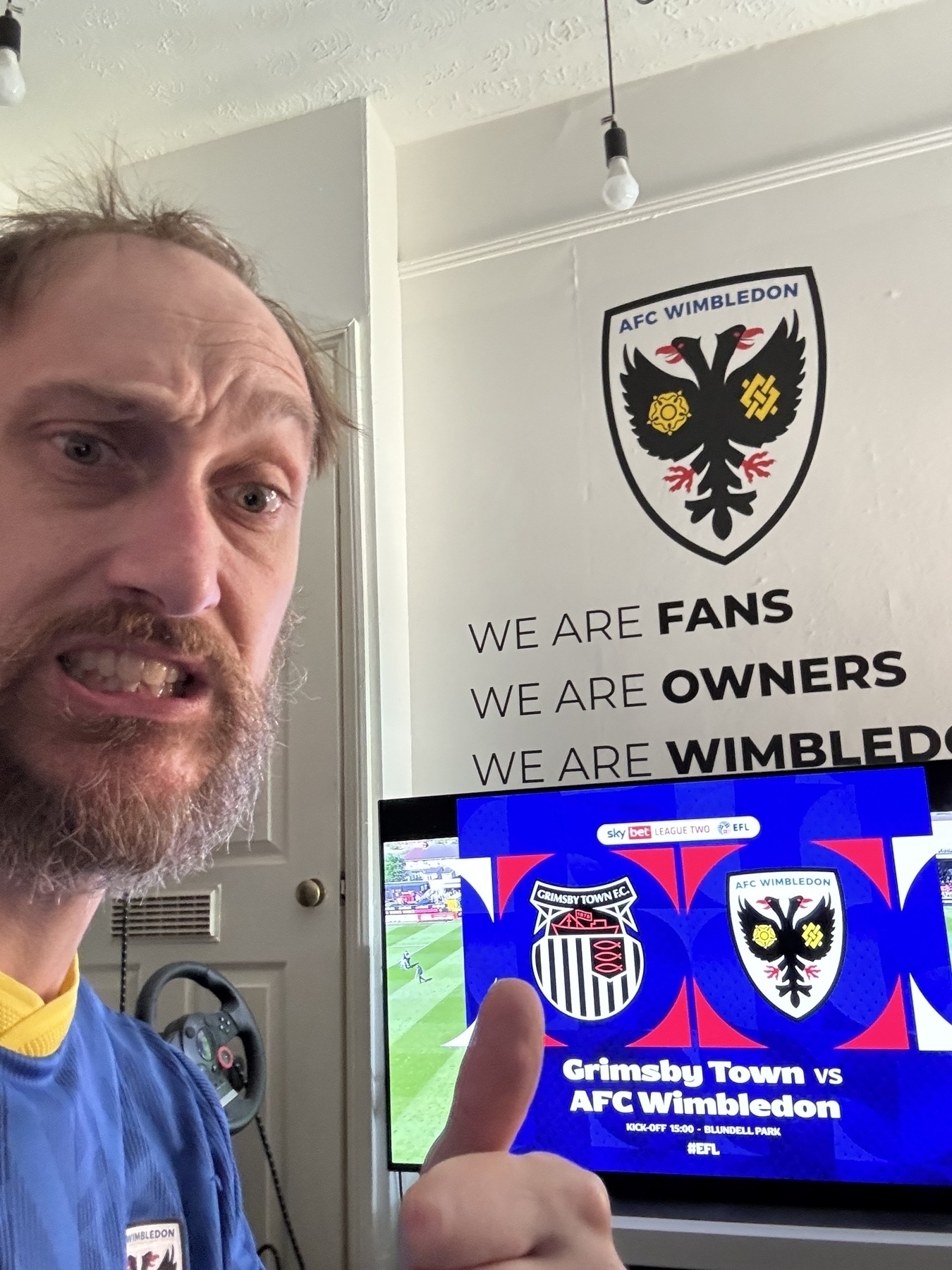 Selfie photo of me (Adam Procter) in front of my TV showing the Wimbledon game and my wall with the Wimbledon mantra&10;&10;We are Fans&10;We are Owners&10;We are Wimbledon