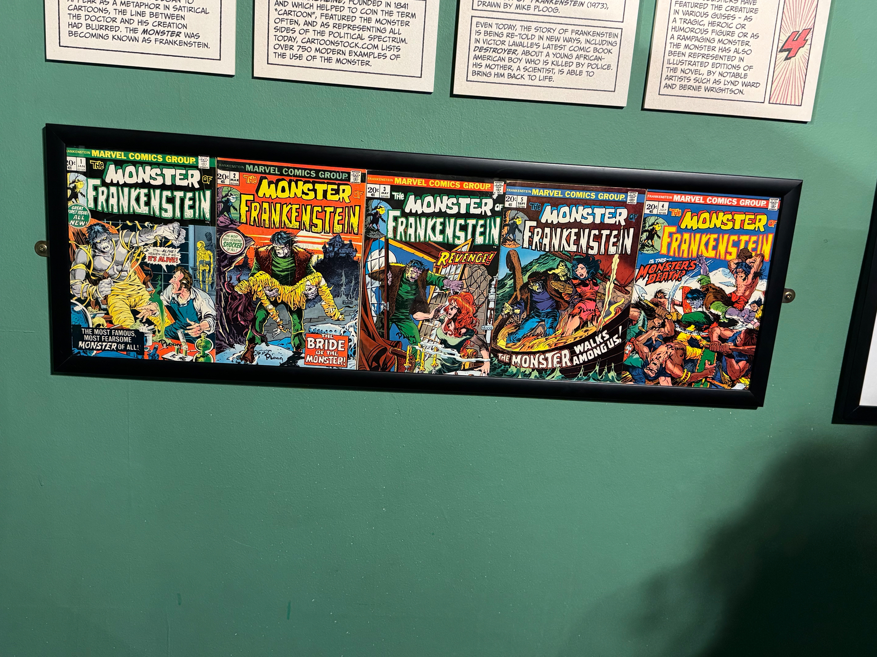 Five vintage comic book covers of Monster of Frankenstein are displayed in a framed arrangement.